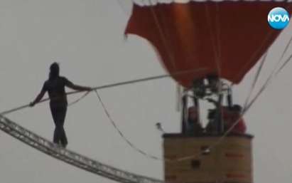 Китаец върви по въже, вързано за балони
